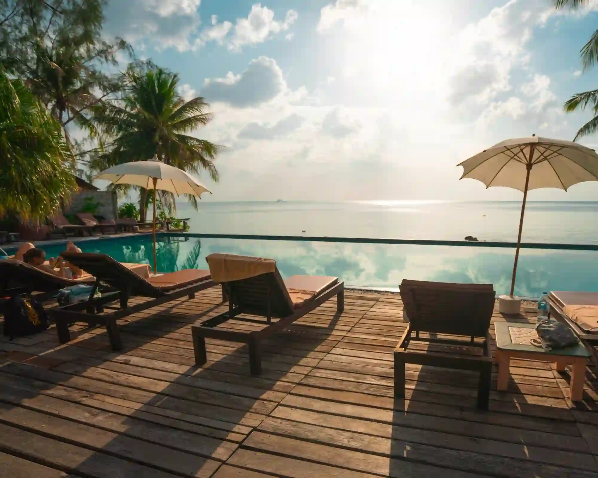 Sunset over a hotel deck with loungers and pool by the sea
