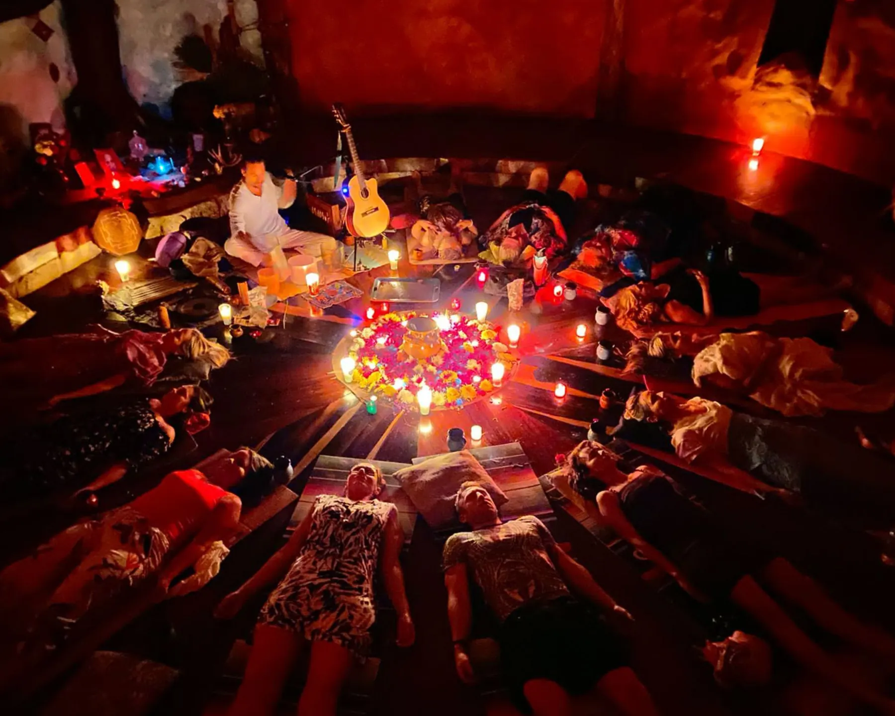 Guests lying in a candlelit circle during an evening ceremony