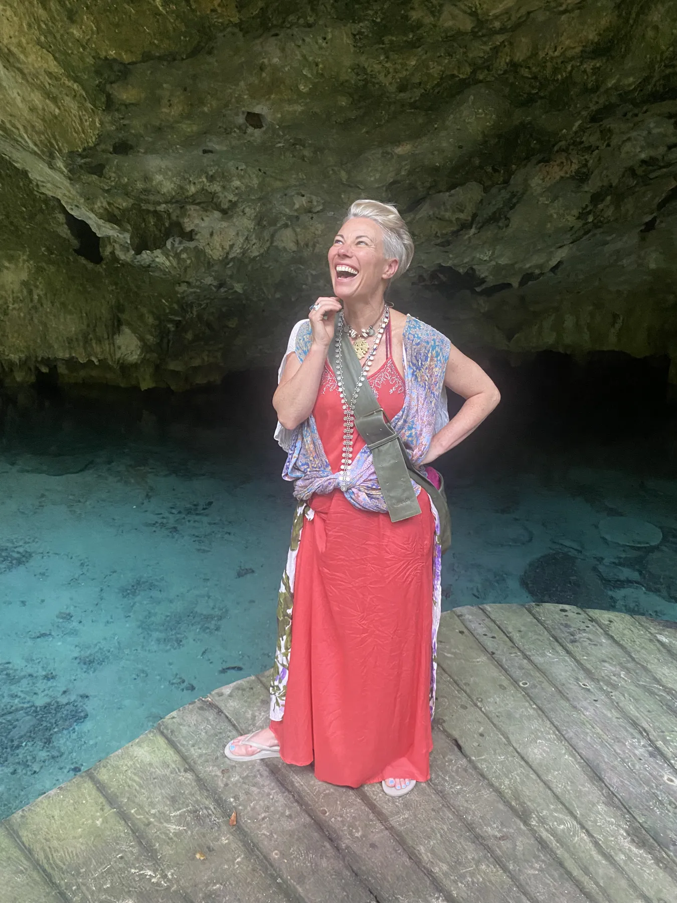 A guest in a red dress laughing at the edge of a cenote
