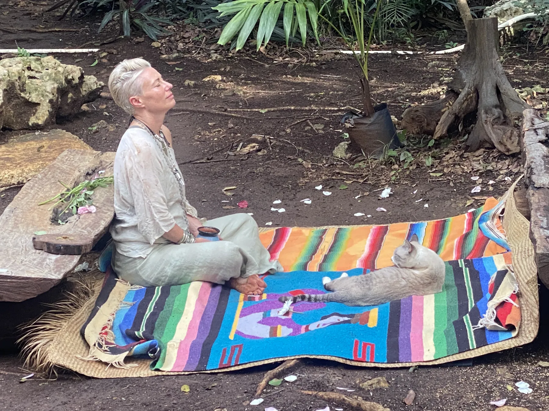 A guest meditating alone on a woven mat in the jungle
