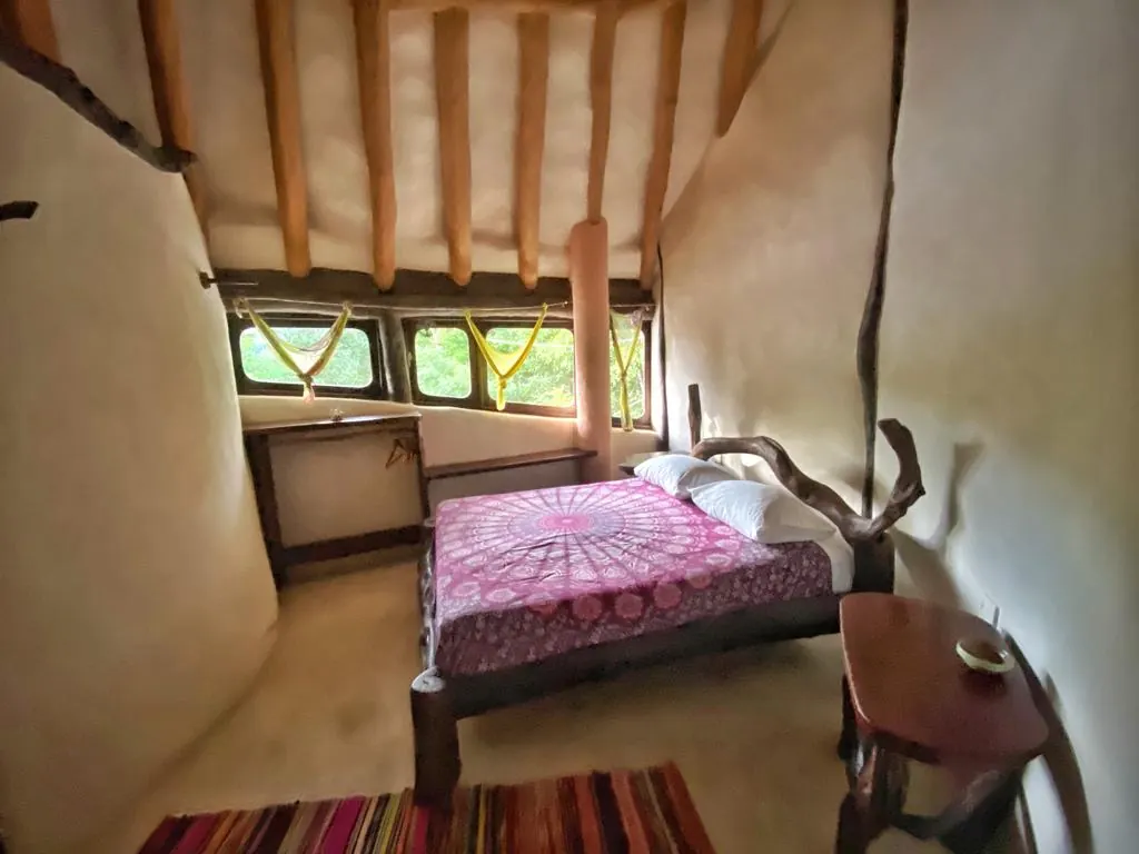 A bright jungle lodge room with a queen bed