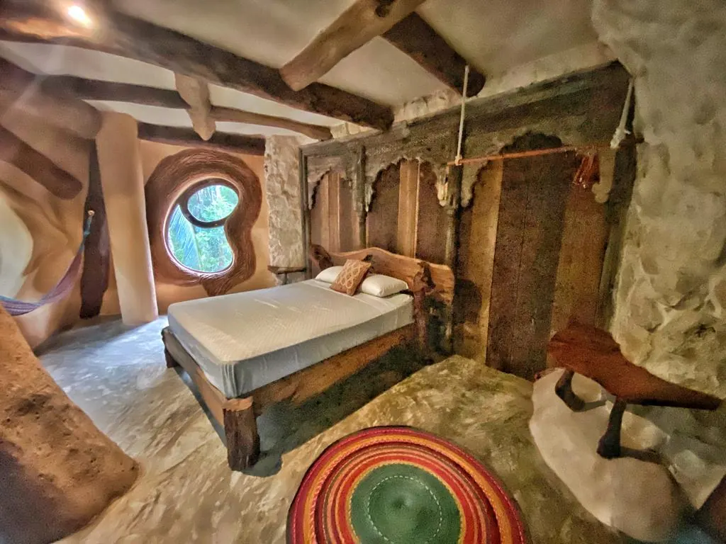 A jungle lodge room with round windows and a queen bed